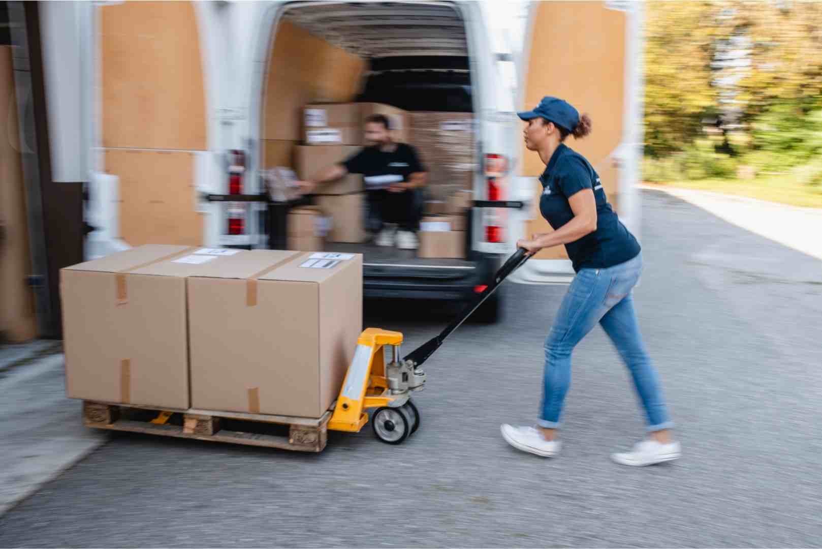 Female delivery driver moving parcels on pallet jack