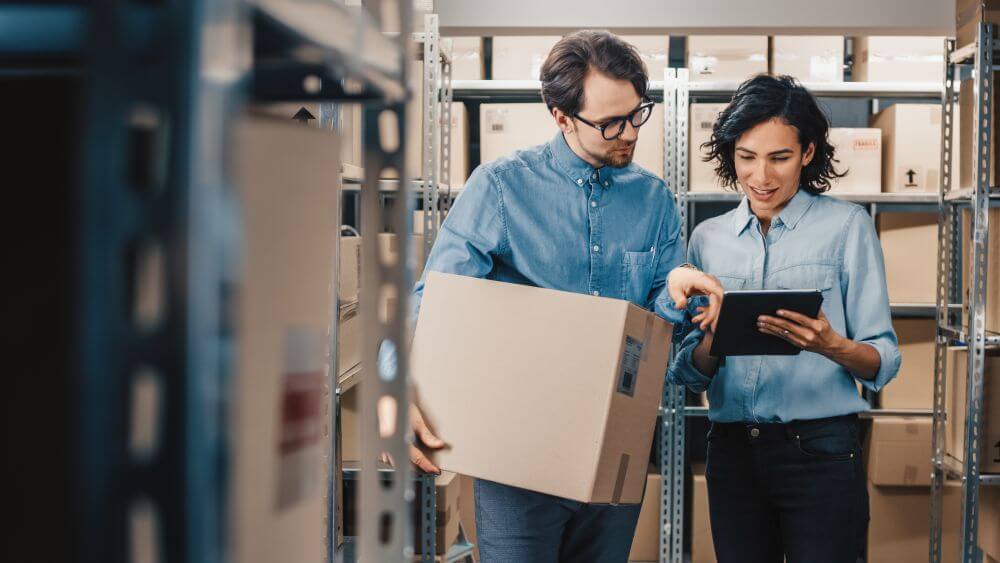 Man and woman in warehouse checking inventory on tablet