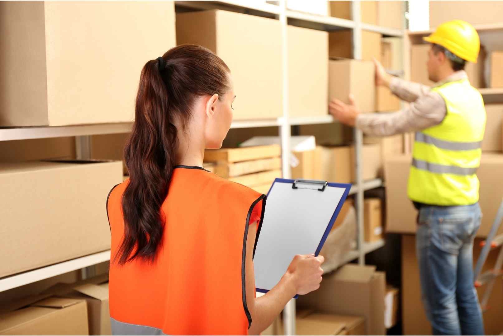 Woman with clipboard standing back at warehouse