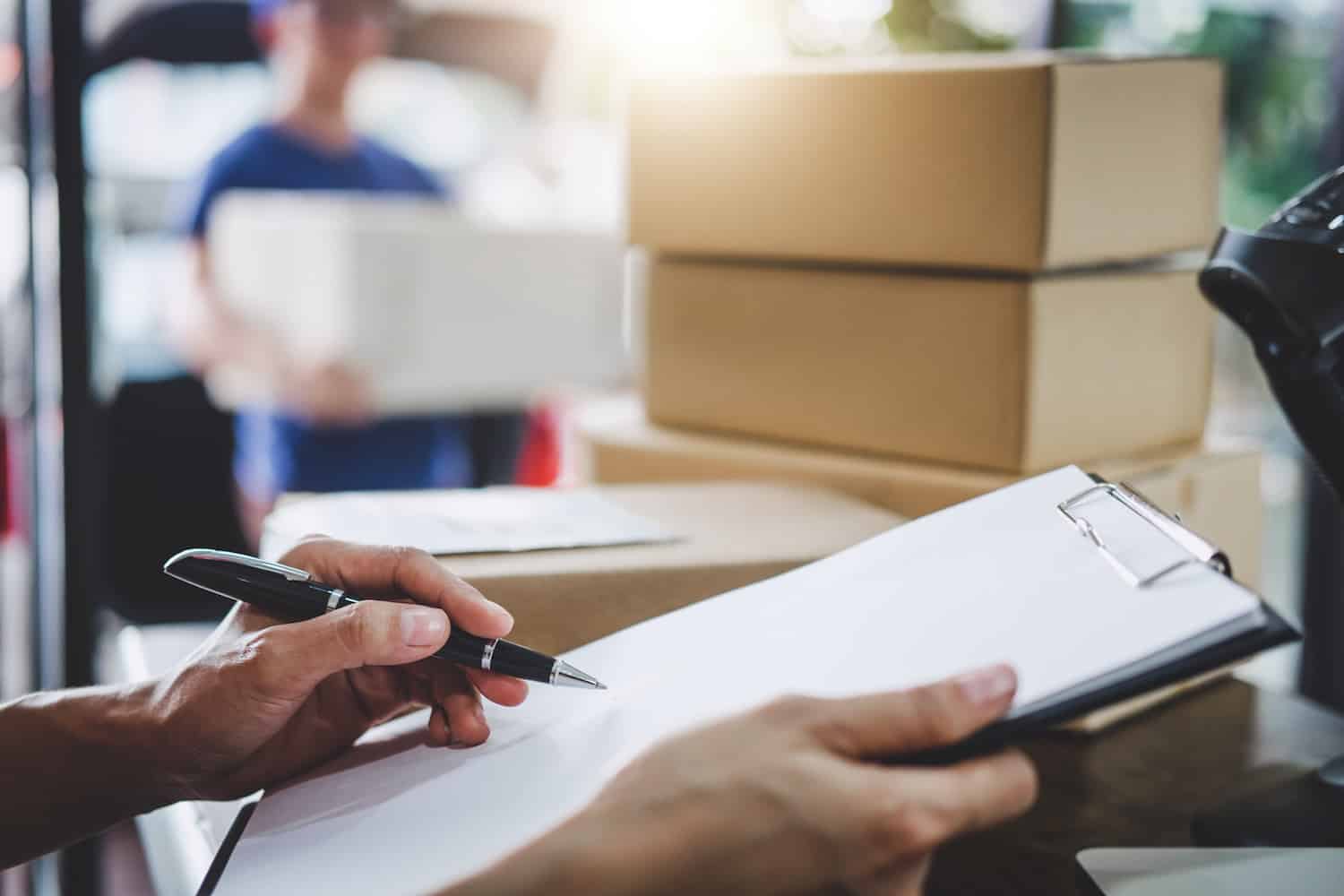 person in a warehouse checks off purchase orders from a clipboard