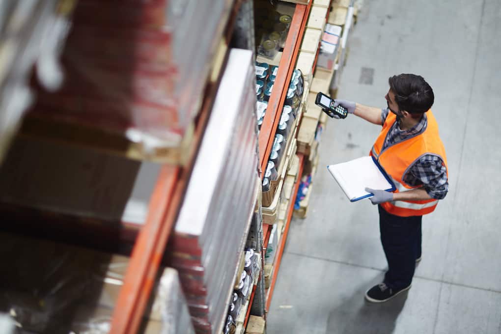 warehouse worker holding a clipboard and scanning an item 