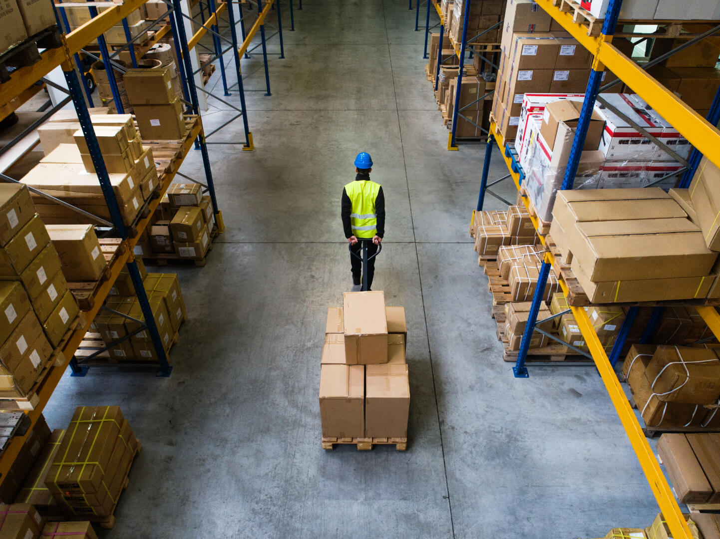 male warehouse worker pulling a pallet truck