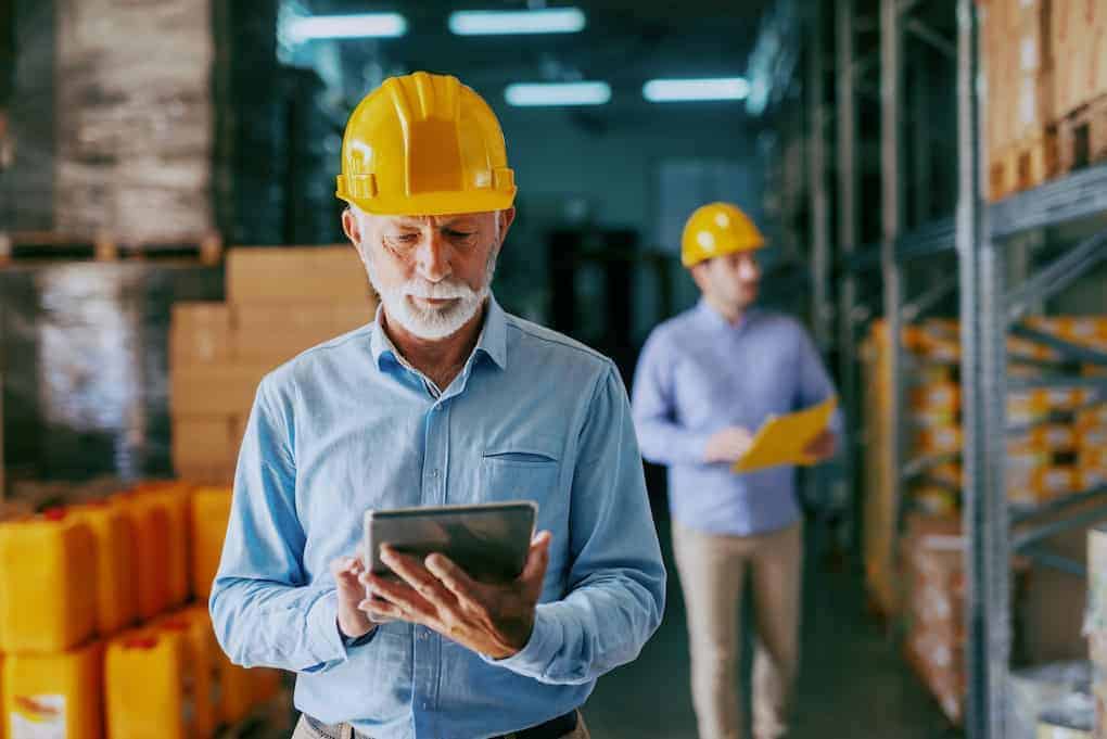 two men in hardhats going over warehouse technology on tablet