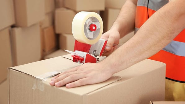 man packing parcels with sticky tape at warehouse