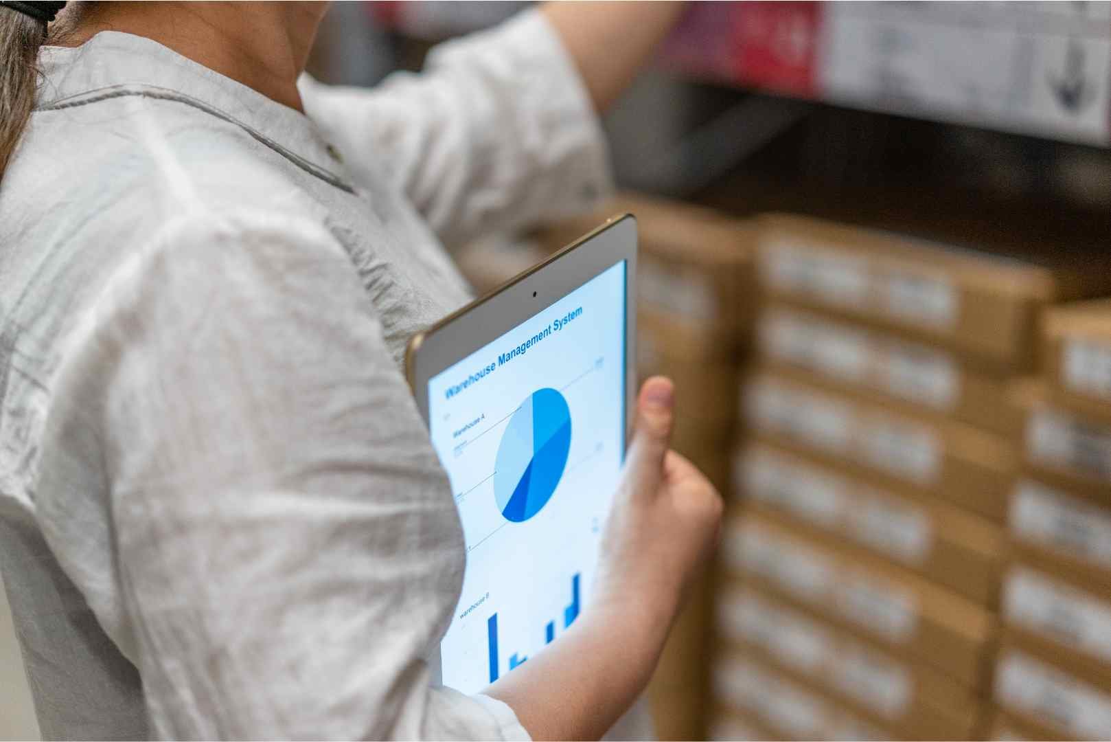 warehouse worker holds a tablet with the WMS application open