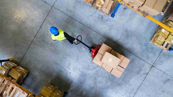 warehouse worker puling a forklift with boxes